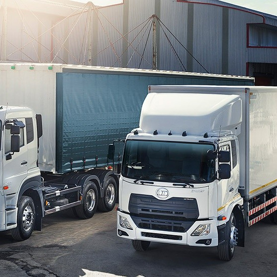 รถบรรทุกสองคันจอดอยู่หน้าคลังสินค้าใต้แสงแดด