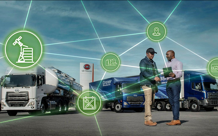 Two people discuss with trucks and digital network icons connecting them.