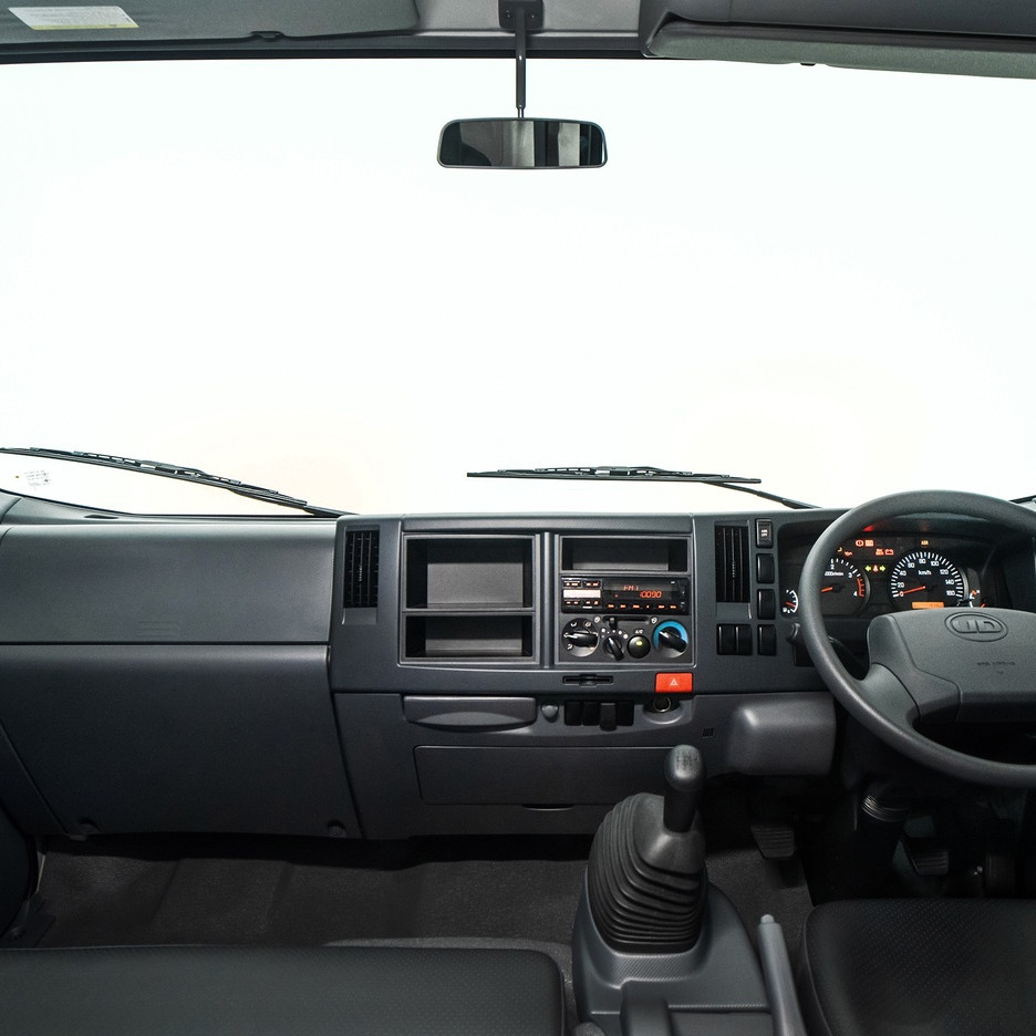 Truck cab interior with steering wheel, dashboard, and gear shift.