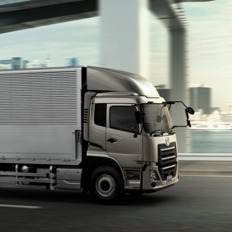 Gray delivery truck driving on a city highway under an overpass.
