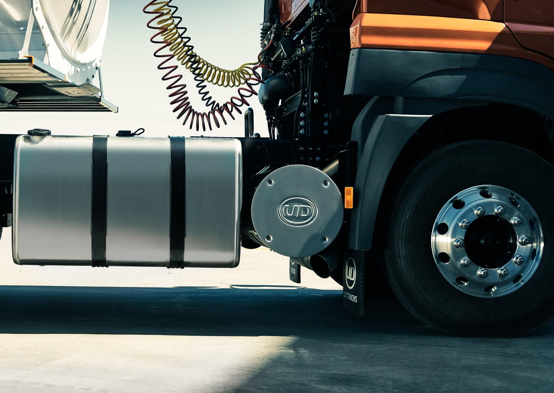 Tayar depan lori besar dengan tangki bahan api logam di tepi jalan.