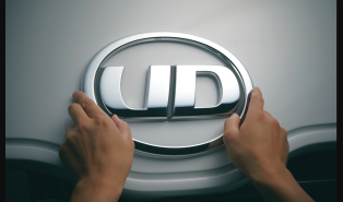 両手でUDトラックスのロゴエンブレムを持つ。